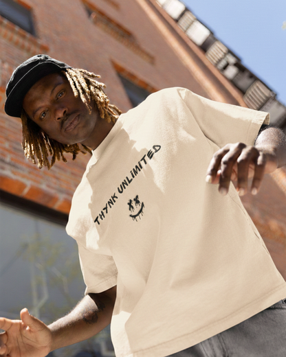 Man wearing a beige t-shirt with text and graphics, standing in an urban setting.
