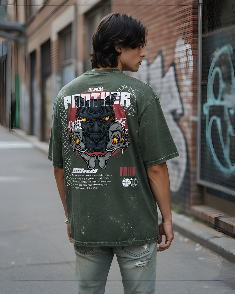 Person wearing a green t-shirt with a Black Panther graphic on the back, standing in an urban setting.